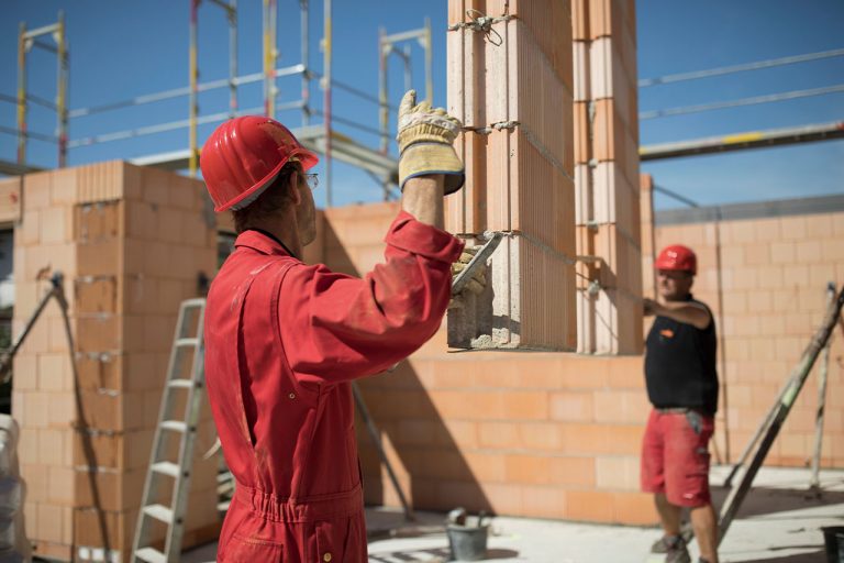 Arbeiter auf einer Baustelle beim vorsichtigen Bewegen schwerer Lasten