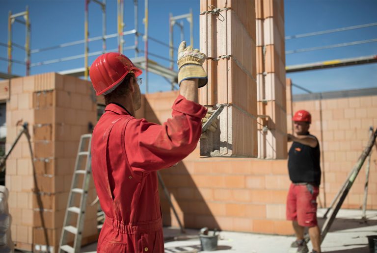 Arbeiter auf einer Baustelle beim vorsichtigen Bewegen schwerer Lasten