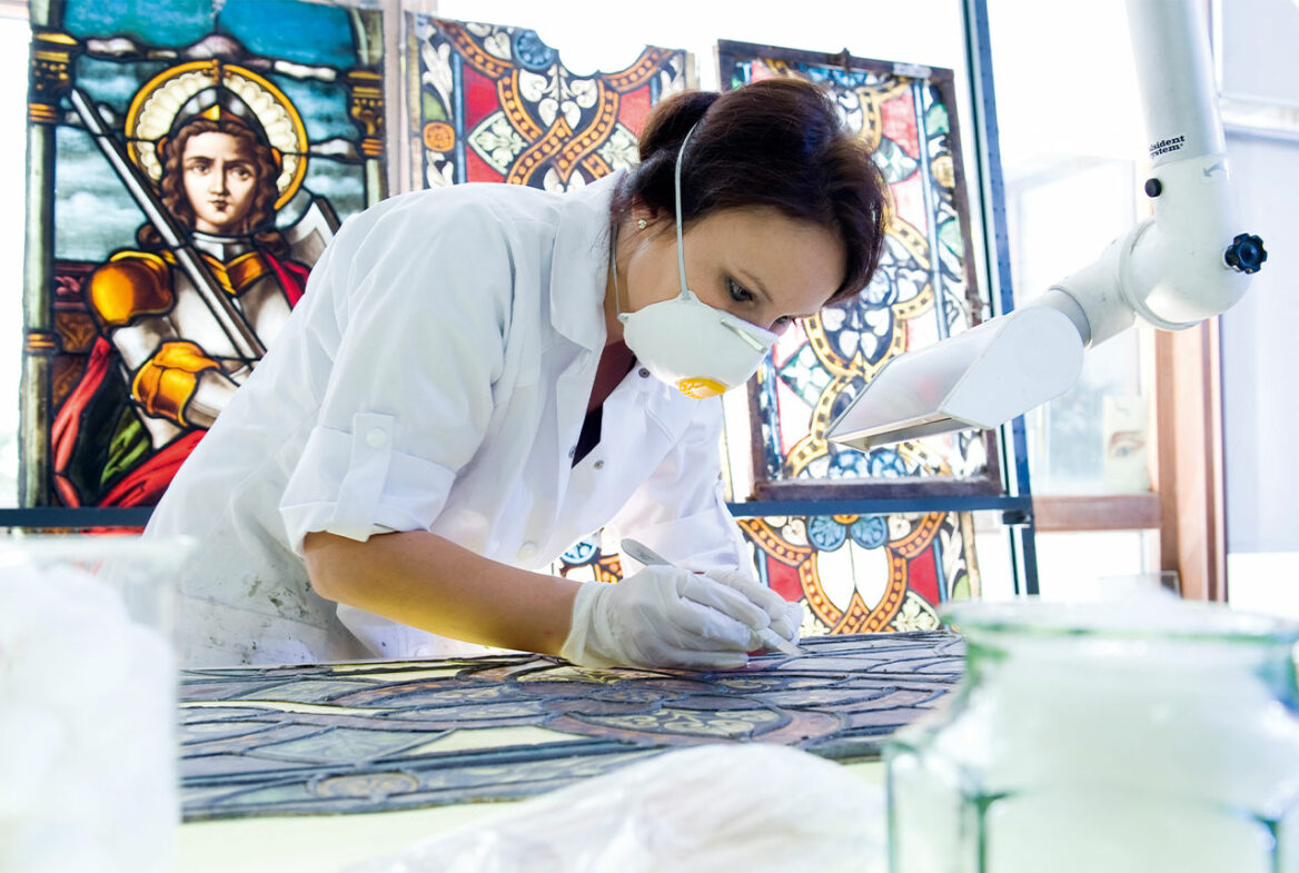 Eine Mitarbeiterin bei der detaillierten Arbeit an einem Bleiglasfenster