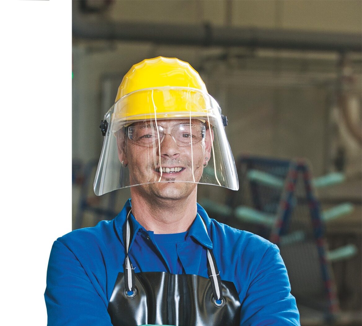 Mitarbeiter mit Handschuhen, Schürze und Schutzhelm mit Visier
